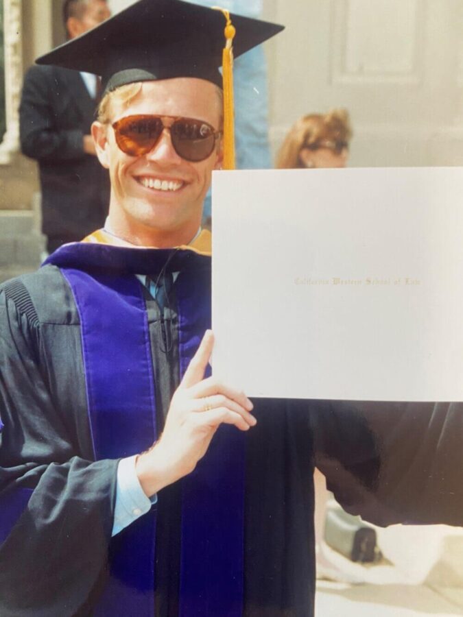 Schuyler Hoffman holding up his diploma after graduating from law school